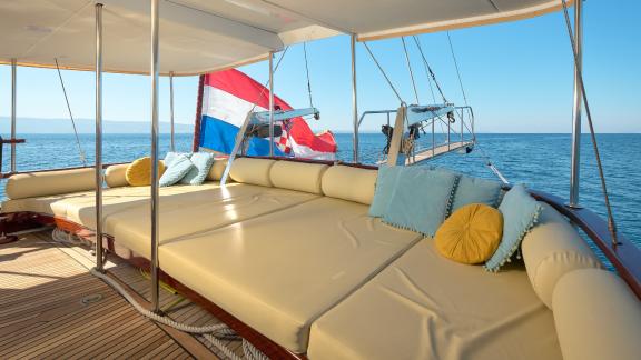 A cosy sunbathing area on the outside deck of the Gulet Linda, with a view of the sea and a Croatian flag in the backgro